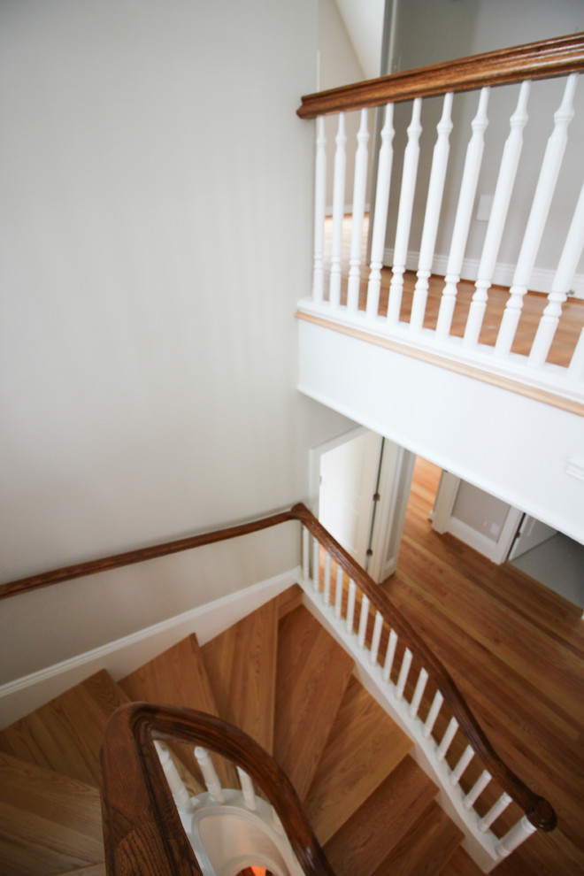 Expansive traditional wood u-shaped wood railing staircase in DC Metro with wood risers.