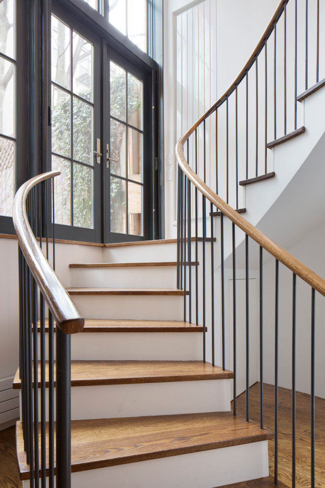 Пример оригинального дизайна: изогнутая лестница в стиле модернизм с деревянными ступенями, крашенными деревянными подступенками и металлическими перилами
