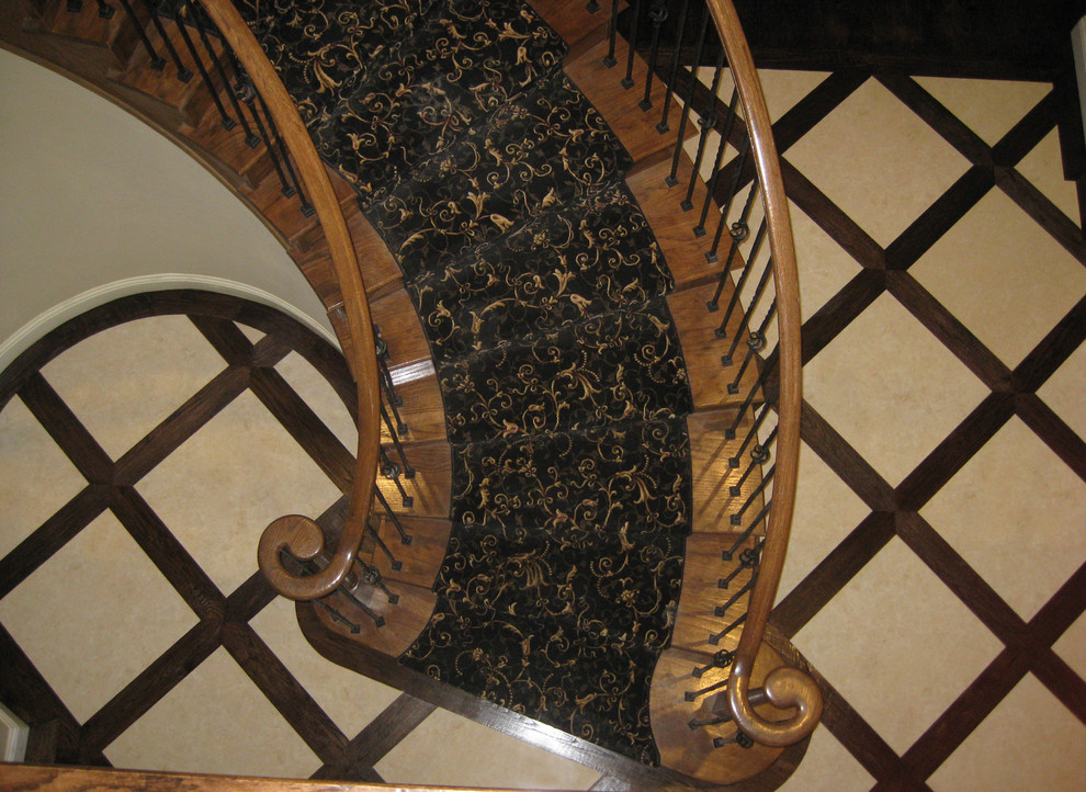 Cette image montre un grand escalier courbe traditionnel avec des marches en moquette, des contremarches en moquette et un garde-corps en métal.