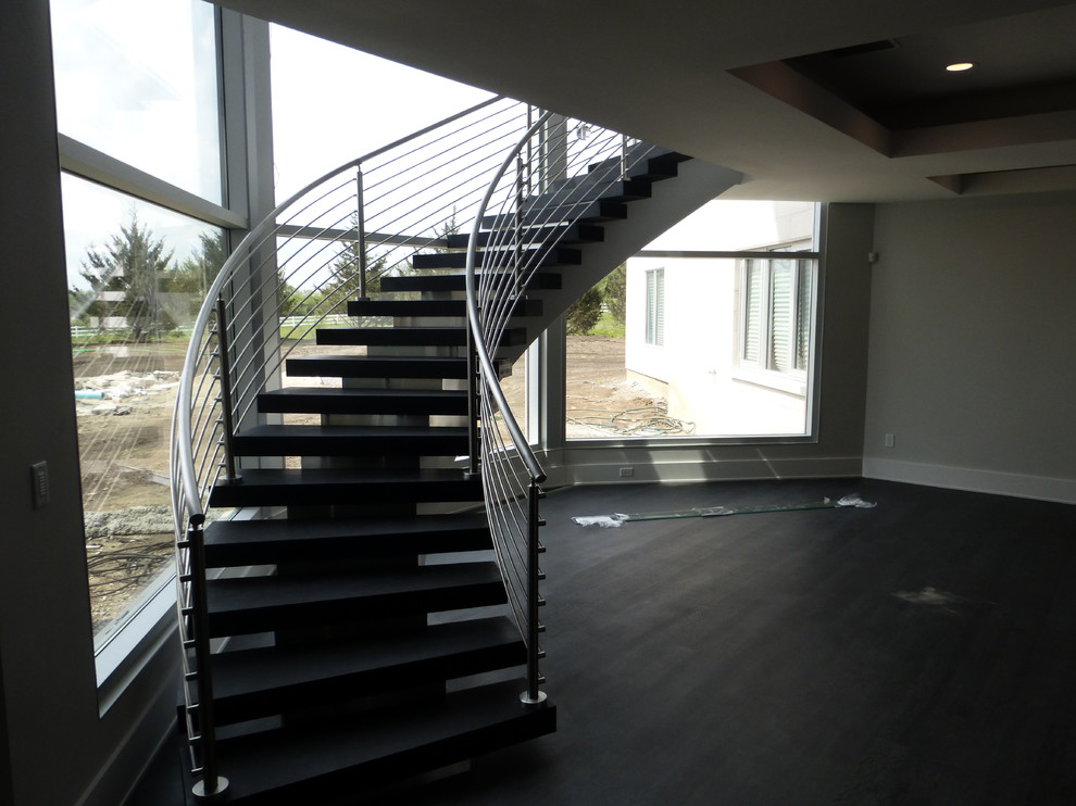 Inspiration pour un grand escalier sans contremarche courbe minimaliste avec des marches en bois peint et un garde-corps en métal.
