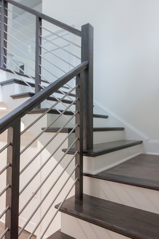 Aménagement d'un grand escalier classique en U avec des marches en bois, des contremarches en bois et un garde-corps en matériaux mixtes.