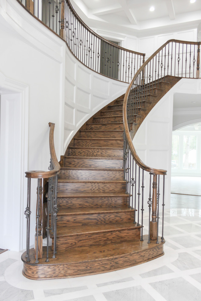 Cette image montre un grand escalier courbe design avec des marches en bois, des contremarches en bois et un garde-corps en matériaux mixtes.