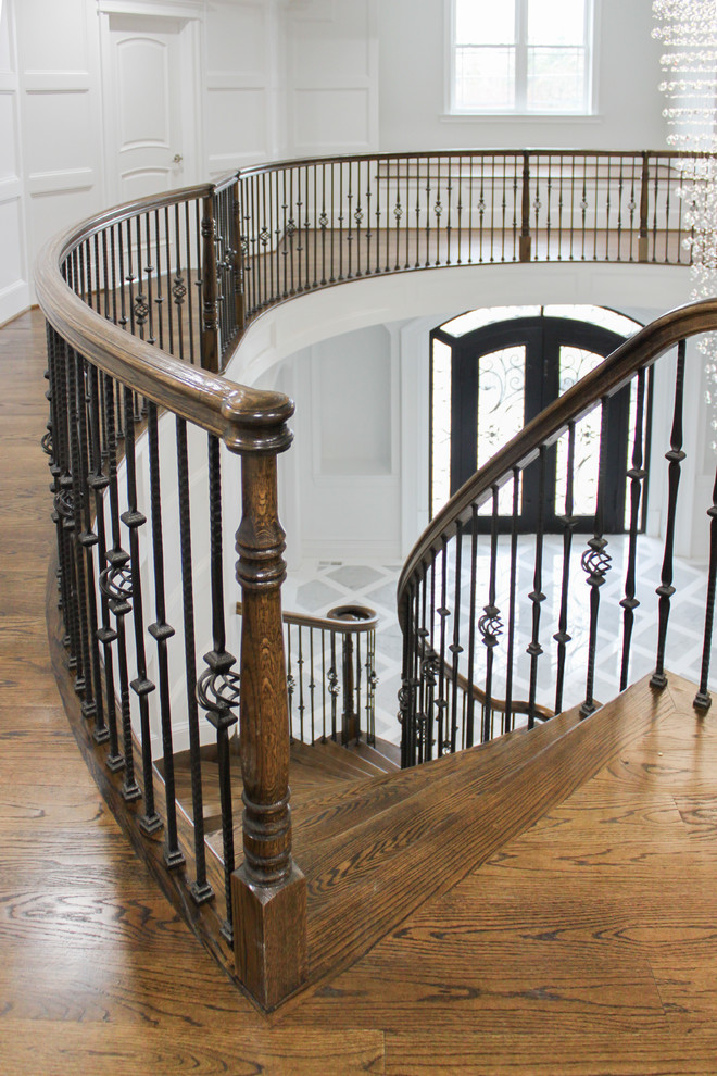 Aménagement d'un grand escalier courbe contemporain avec des marches en bois, des contremarches en bois et un garde-corps en matériaux mixtes.