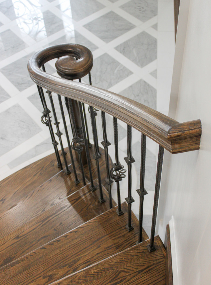 Aménagement d'un grand escalier courbe contemporain avec des marches en bois, des contremarches en bois et un garde-corps en matériaux mixtes.