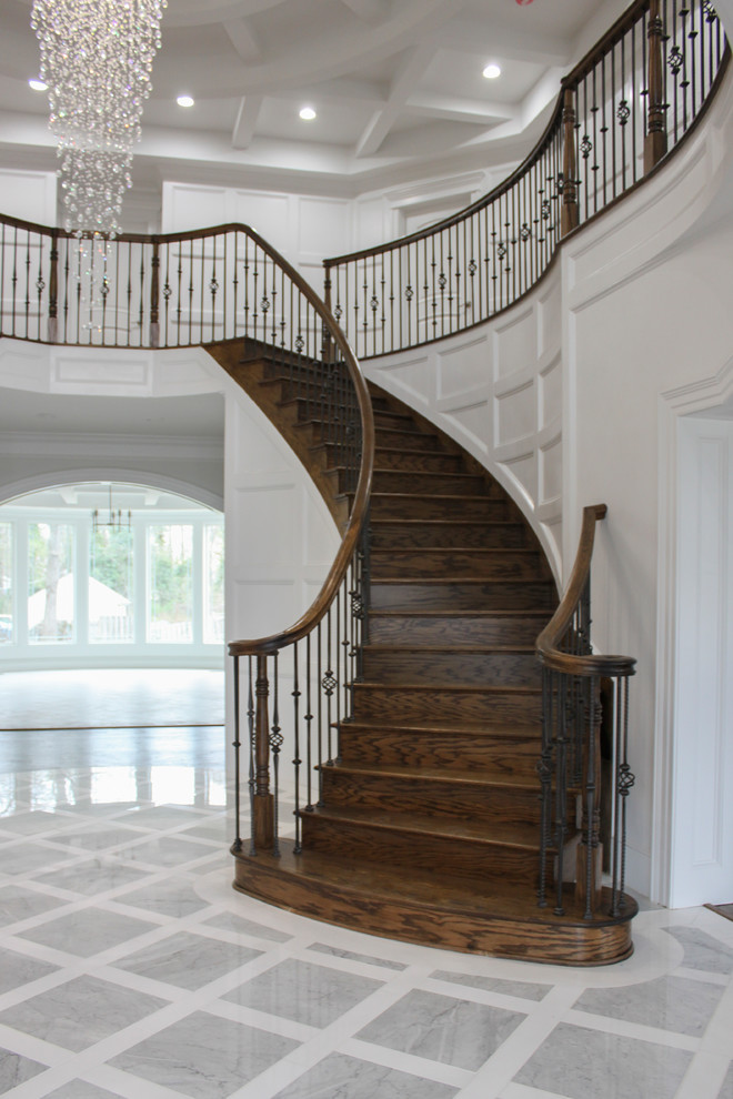 Réalisation d'un grand escalier courbe design avec des marches en bois, des contremarches en bois et un garde-corps en matériaux mixtes.