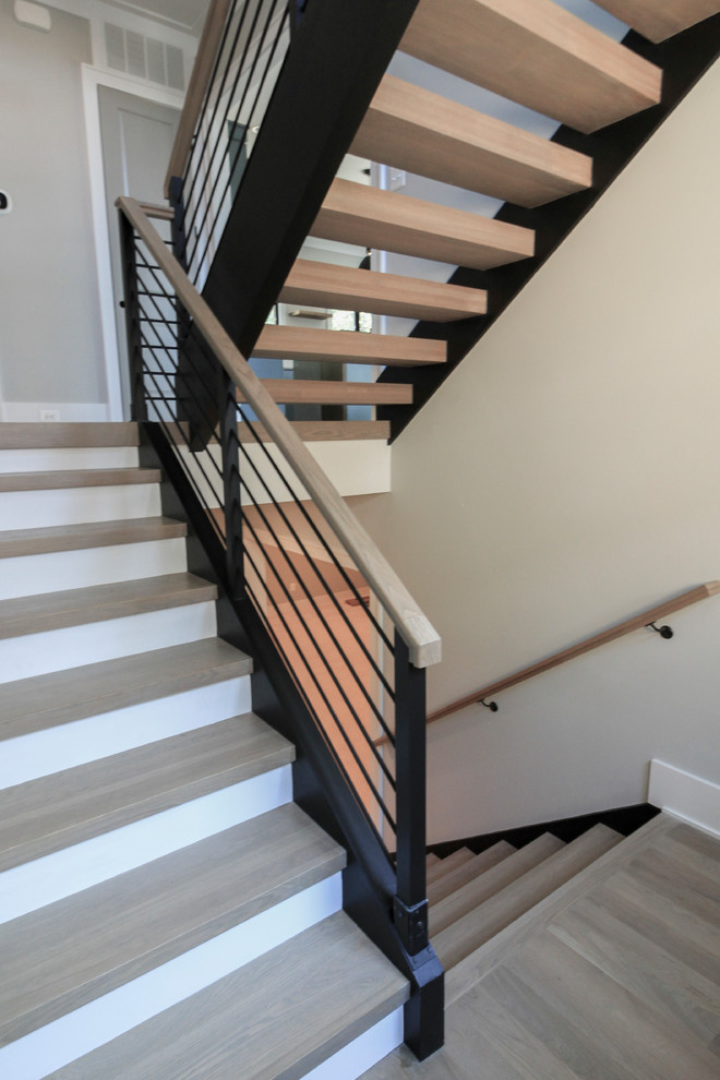 Cette image montre un grand escalier flottant minimaliste avec des marches en bois et un garde-corps en matériaux mixtes.