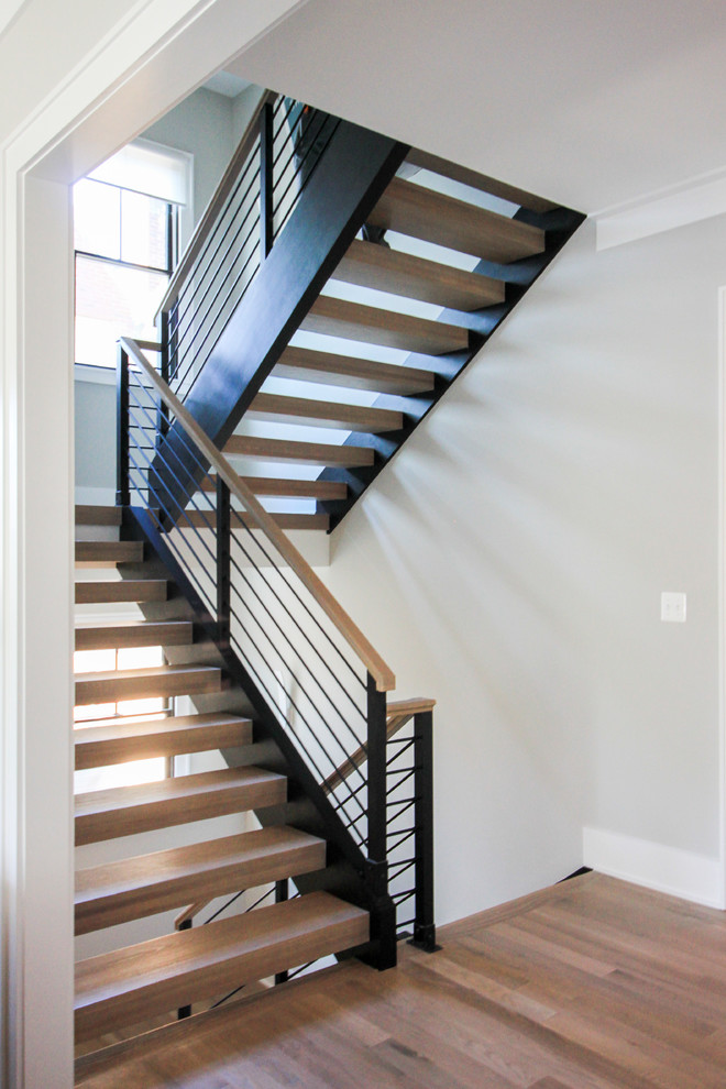Imagen de escalera suspendida moderna grande con escalones de madera y barandilla de varios materiales