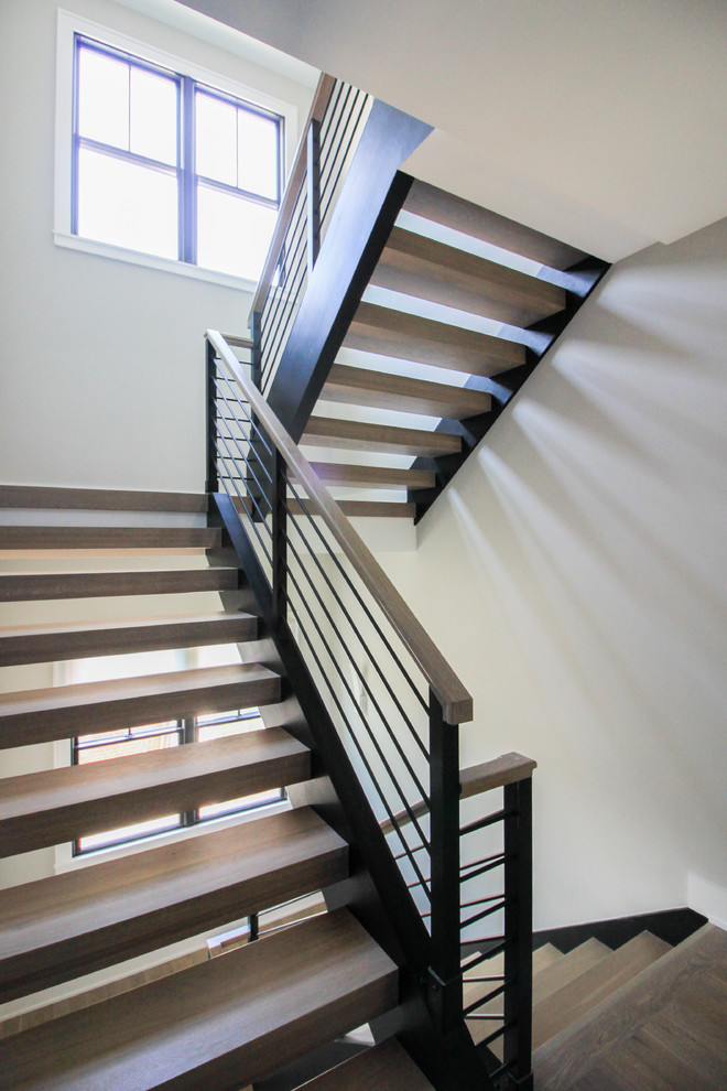 Ejemplo de escalera suspendida minimalista grande con escalones de madera y barandilla de varios materiales