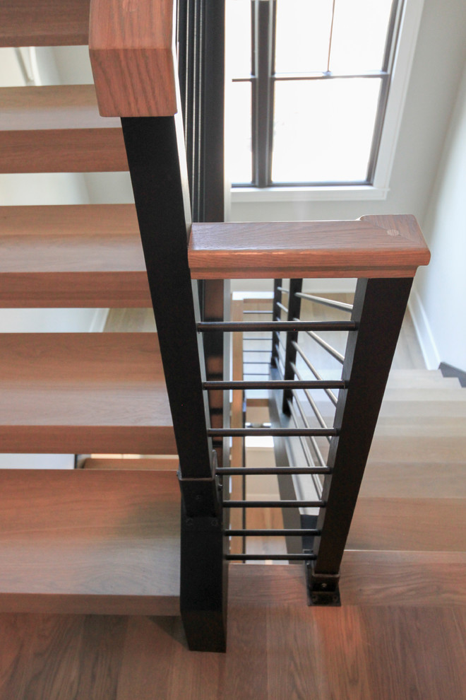 Diseño de escalera suspendida minimalista grande con escalones de madera y barandilla de varios materiales