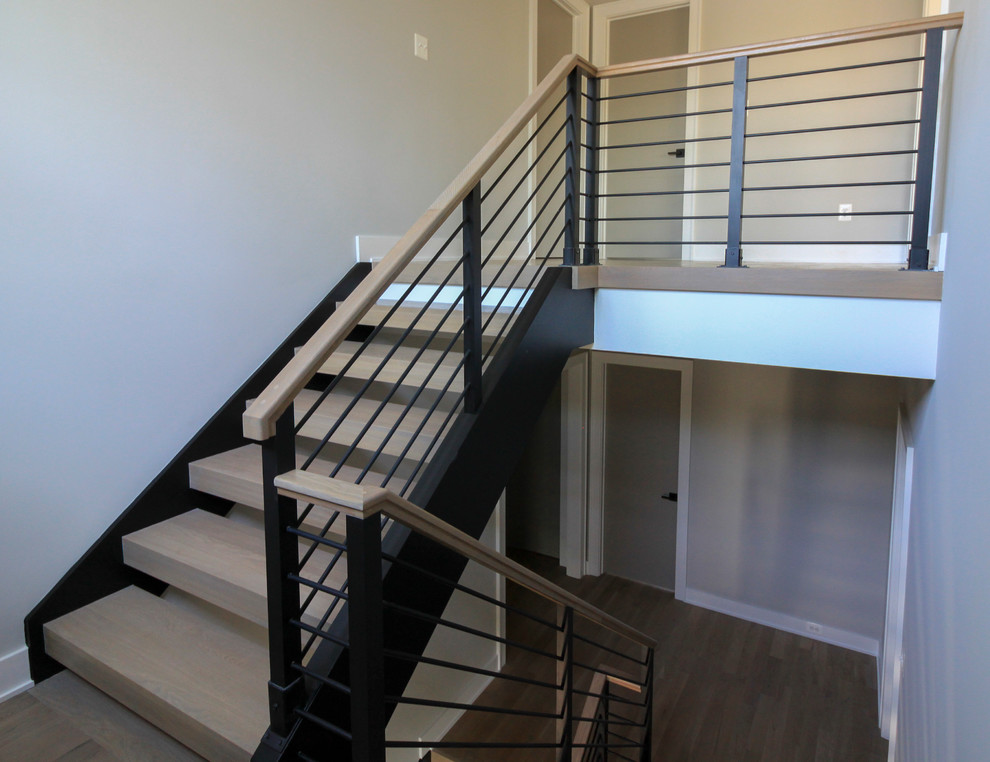 На фото: большая лестница на больцах в стиле модернизм с деревянными ступенями и перилами из смешанных материалов с