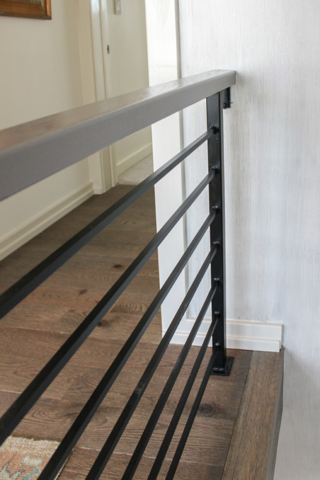 Photo of a large eclectic wood floating metal railing staircase in DC Metro with wood risers.