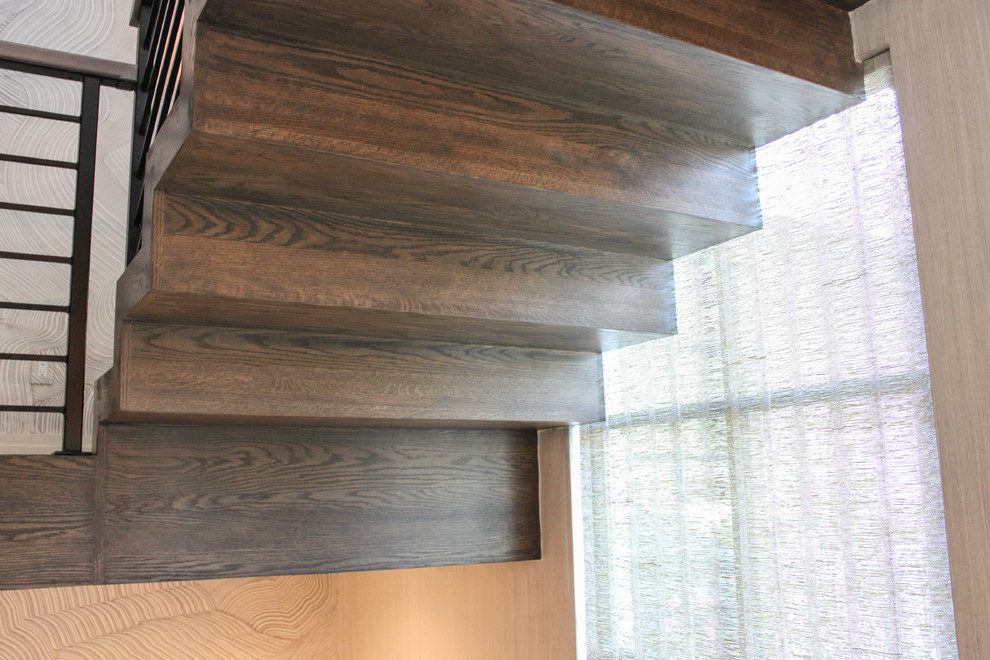Eklektisk inredning av en stor flytande trappa i trä, med sättsteg i trä och räcke i metall