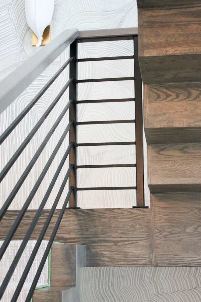 Cette image montre un grand escalier flottant bohème avec des marches en bois, des contremarches en bois et un garde-corps en métal.