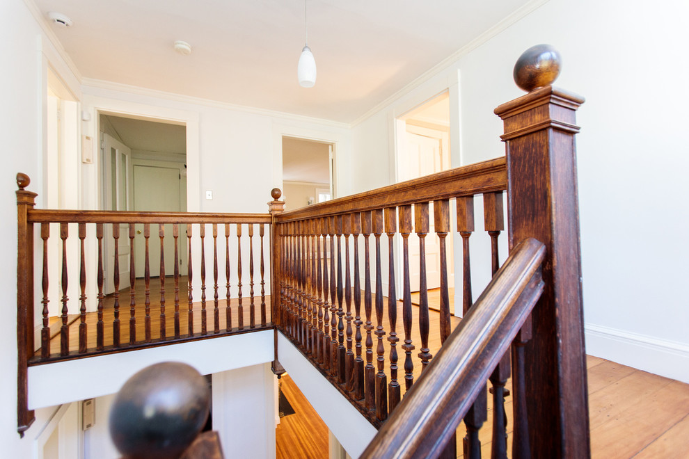 Imagen de escalera en L tradicional grande con escalones de madera, contrahuellas de madera y barandilla de madera