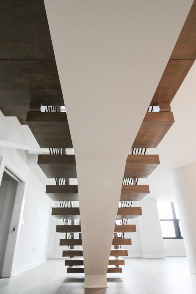 Cette image montre un grand escalier design en U avec des marches en bois et un garde-corps en câble.
