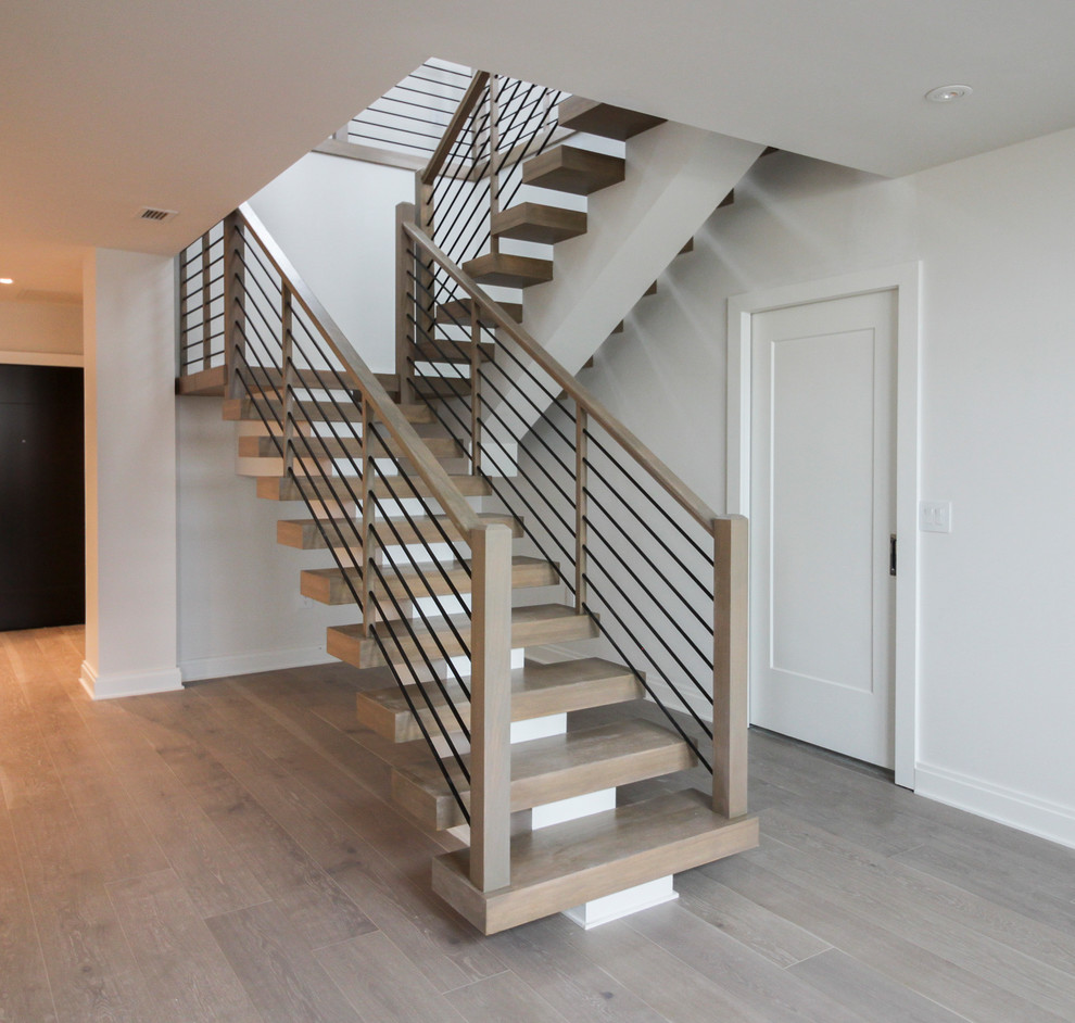 Idée de décoration pour un grand escalier design en U avec des marches en bois et un garde-corps en câble.