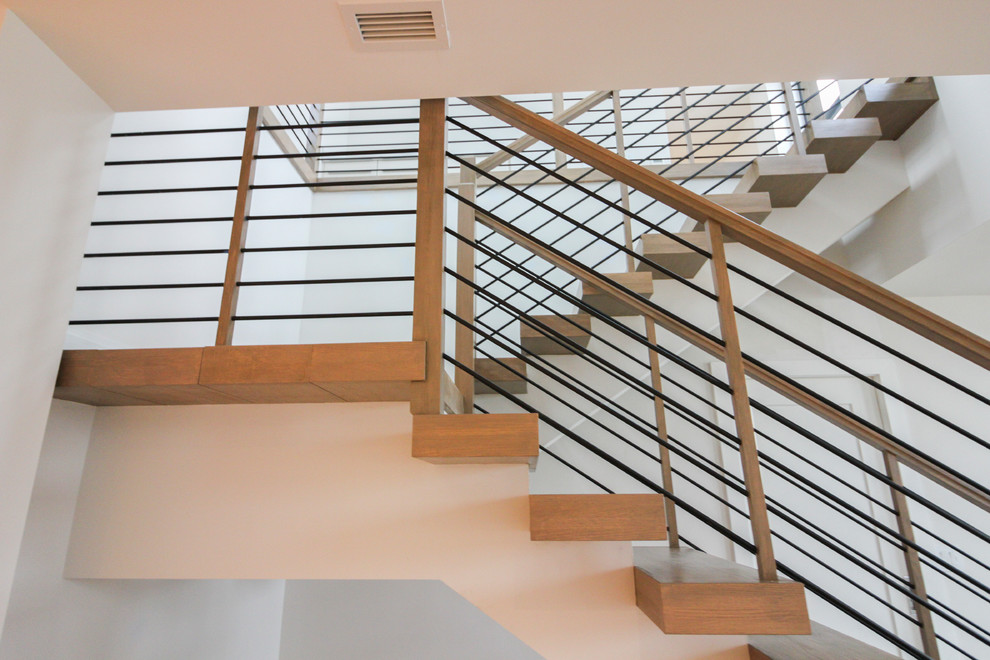 Idée de décoration pour un grand escalier design en U avec des marches en bois et un garde-corps en câble.