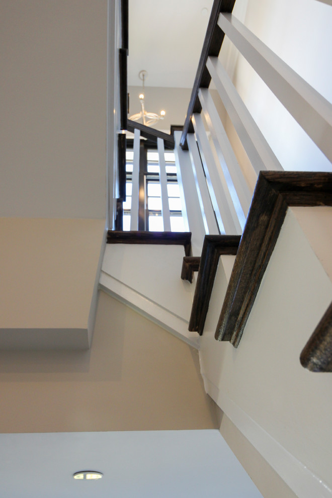 Imagen de escalera en U minimalista de tamaño medio con escalones de travertino, contrahuellas de madera y barandilla de madera