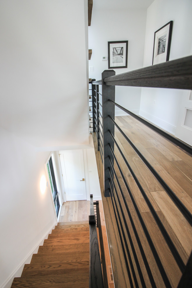 Réalisation d'un grand escalier droit minimaliste avec des marches en bois, des contremarches en bois et un garde-corps en matériaux mixtes.