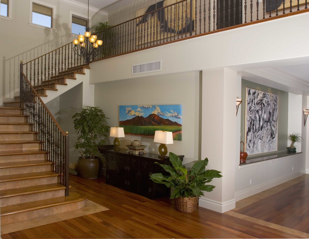 Ejemplo de escalera en L tropical grande con escalones de madera, contrahuellas con baldosas y/o azulejos y barandilla de madera