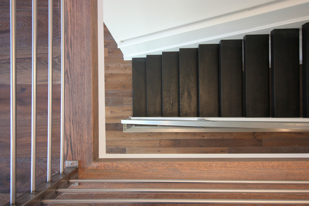 Ejemplo de escalera suspendida contemporánea grande con escalones de madera y barandilla de metal