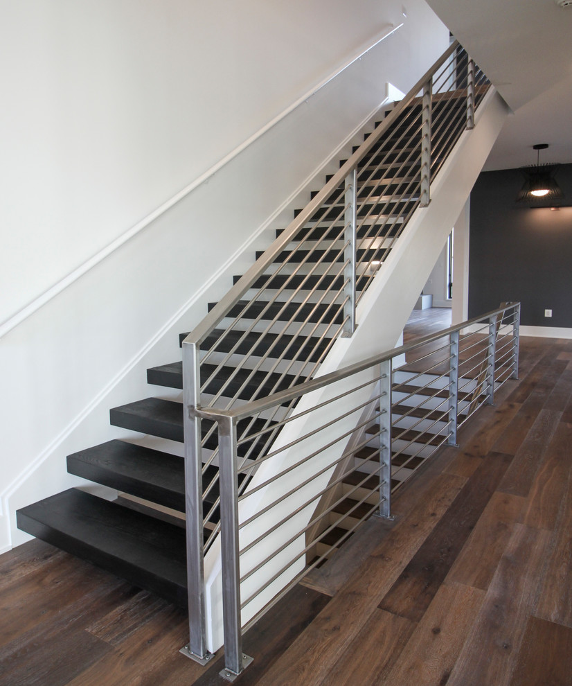 На фото: большая лестница на больцах в современном стиле с деревянными ступенями и металлическими перилами с