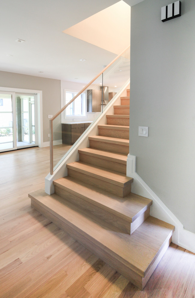 Aménagement d'un petit escalier droit contemporain avec des marches en bois, des contremarches en bois et un garde-corps en verre.