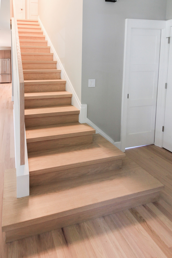 Diseño de escalera recta actual pequeña con escalones de madera, contrahuellas de madera y barandilla de vidrio