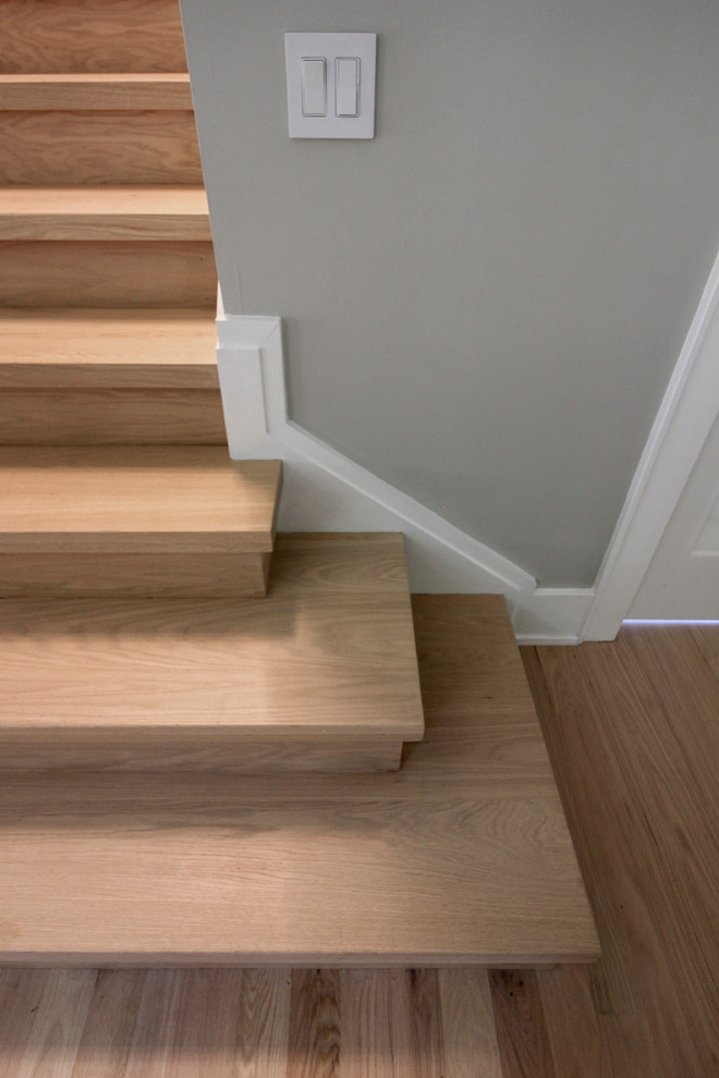 Imagen de escalera recta contemporánea pequeña con escalones de madera, contrahuellas de madera y barandilla de vidrio