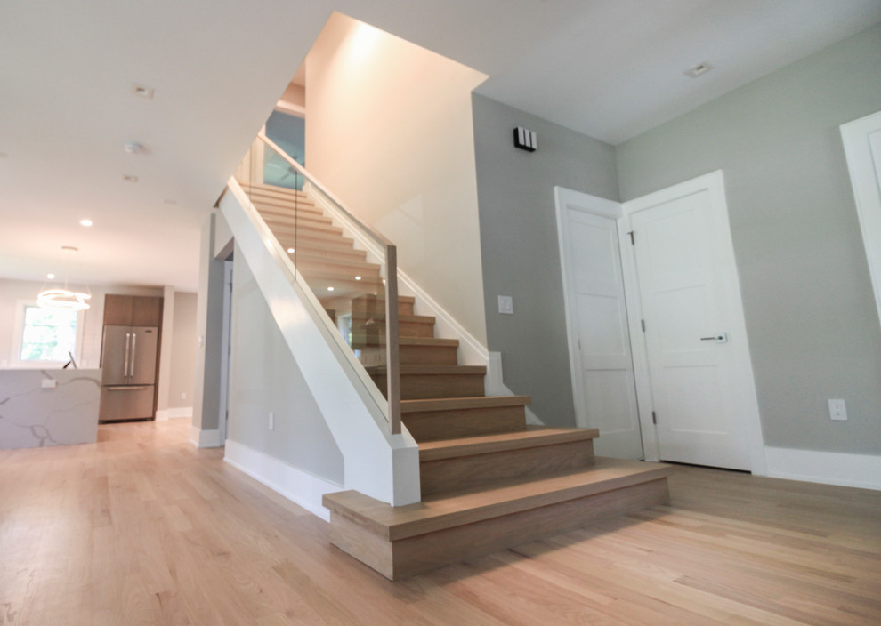 Inspiration pour un petit escalier droit design avec des marches en bois, des contremarches en bois et un garde-corps en verre.