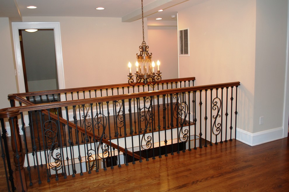 Пример оригинального дизайна: большая лестница в классическом стиле с деревянными ступенями и крашенными деревянными подступенками