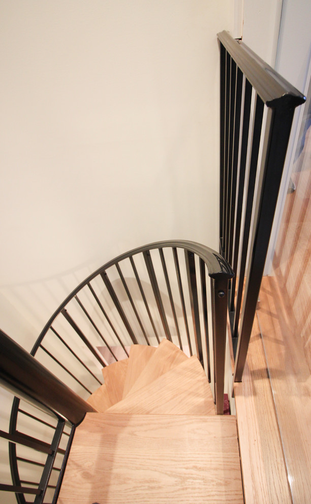 Réalisation d'un petit escalier hélicoïdal design avec des marches en bois et un garde-corps en métal.