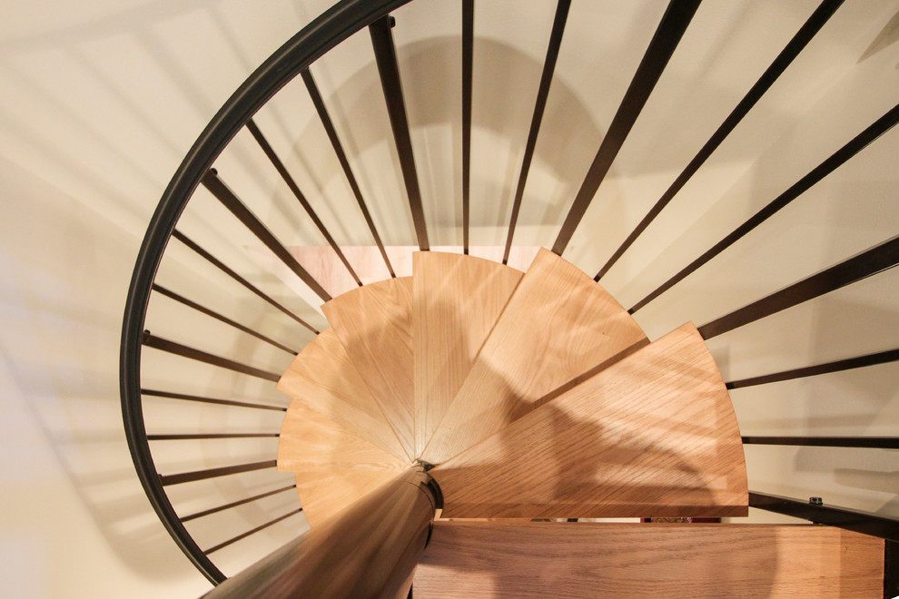 Cette photo montre un petit escalier hélicoïdal tendance avec des marches en bois et un garde-corps en métal.