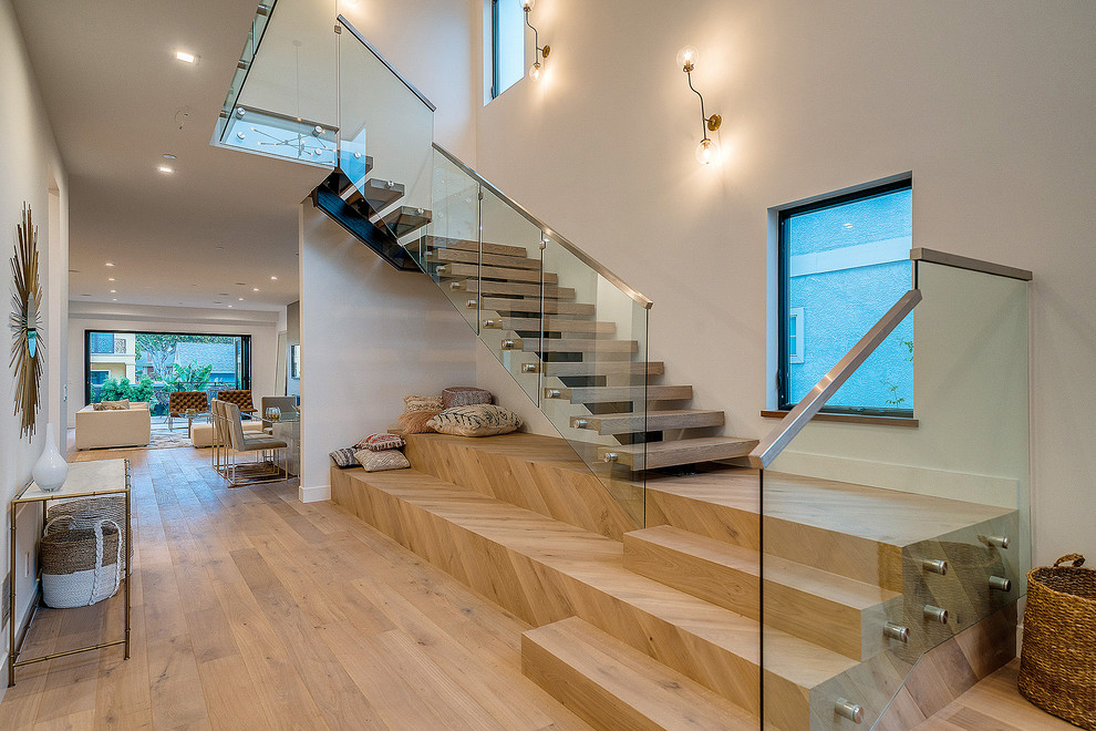 Diseño de escalera en L actual sin contrahuella con escalones de madera y barandilla de vidrio
