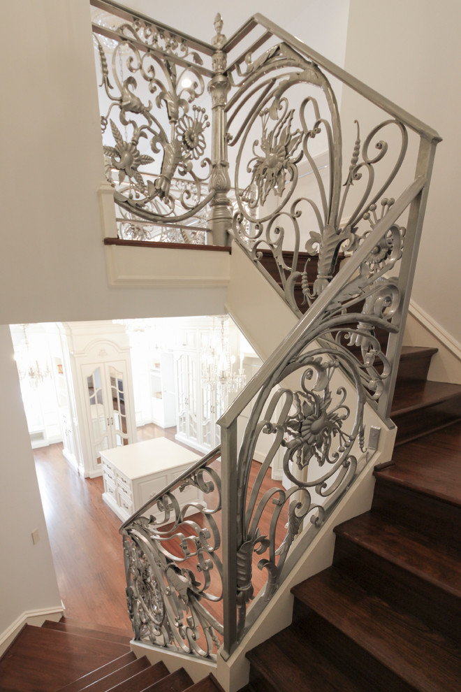 Imagen de escalera curva tradicional extra grande con escalones de madera, contrahuellas de madera y barandilla de metal