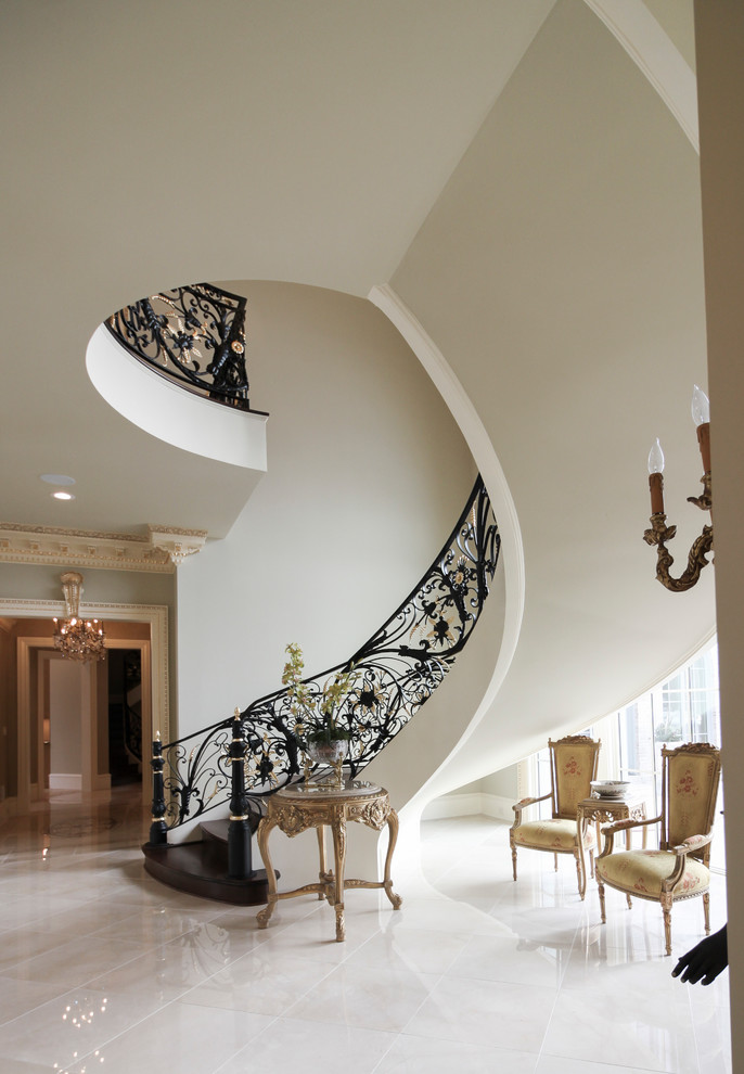 Свежая идея для дизайна: огромная изогнутая деревянная лестница в классическом стиле с деревянными ступенями и металлическими перилами - отличное фото интерьера