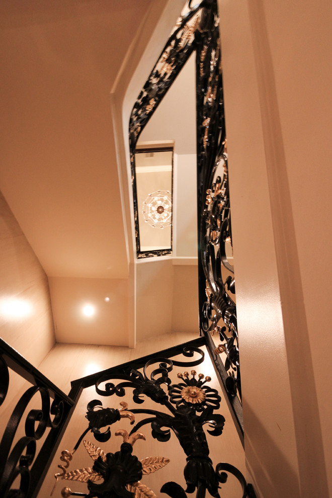 Стильный дизайн: огромная изогнутая деревянная лестница в классическом стиле с деревянными ступенями и металлическими перилами - последний тренд