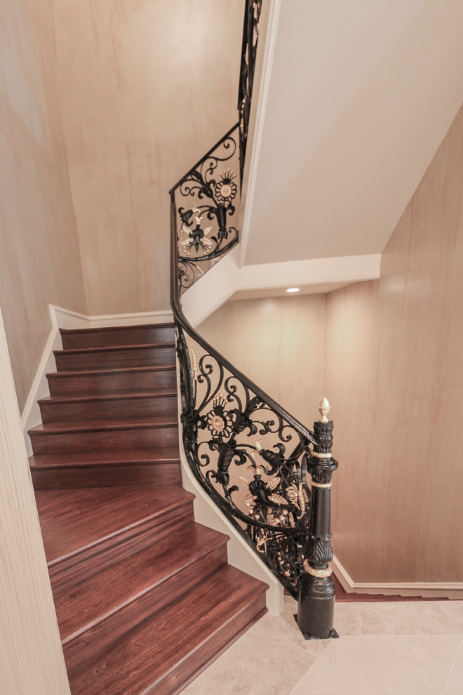 Ejemplo de escalera curva tradicional extra grande con escalones de madera, contrahuellas de madera y barandilla de metal