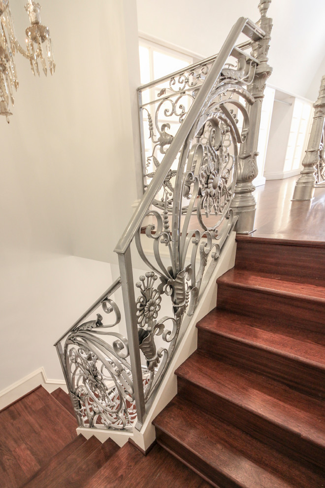 Imagen de escalera curva tradicional extra grande con escalones de madera, contrahuellas de madera y barandilla de metal