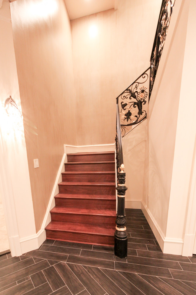 Ejemplo de escalera curva clásica extra grande con escalones de madera, contrahuellas de madera y barandilla de metal