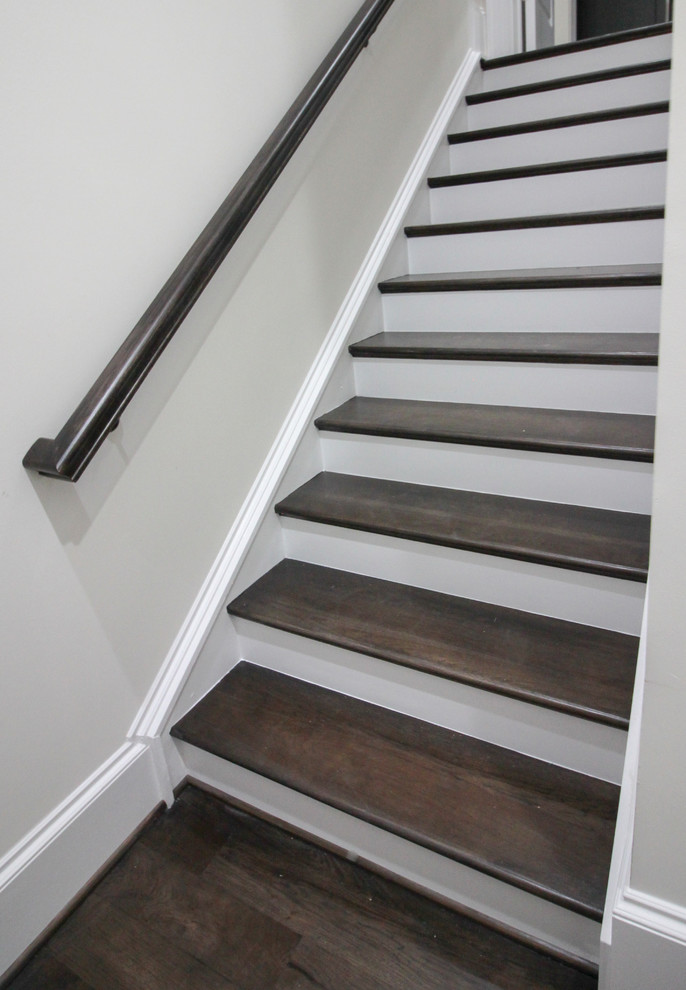 Modelo de escalera suspendida clásica renovada grande con escalones de madera, contrahuellas de madera y barandilla de vidrio