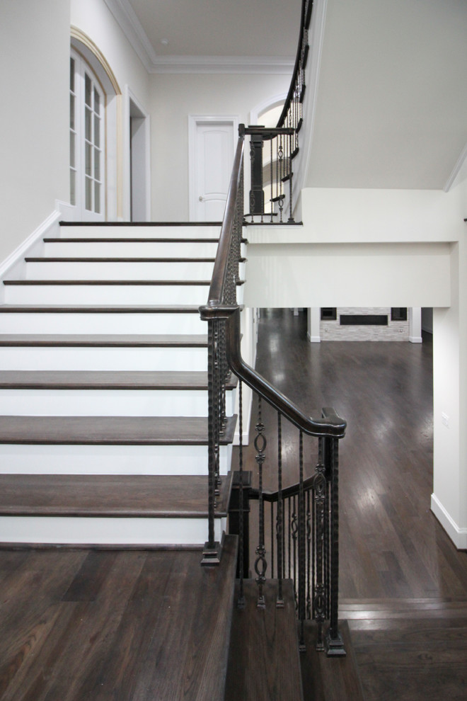 Modelo de escalera suspendida clásica renovada grande con escalones de madera, contrahuellas de madera y barandilla de vidrio