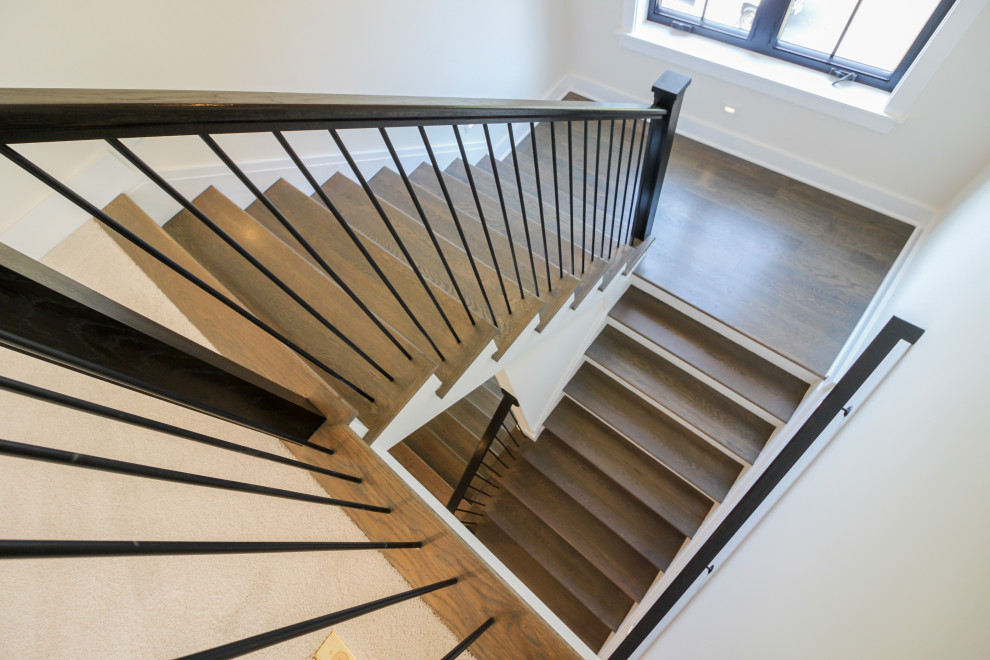 Medium sized contemporary wood u-shaped metal railing staircase in DC Metro with wood risers.