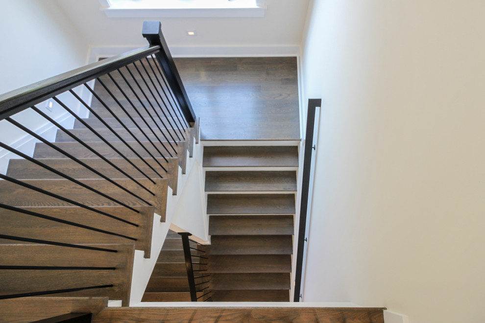 Imagen de escalera en U actual de tamaño medio con escalones de madera, contrahuellas de madera y barandilla de metal