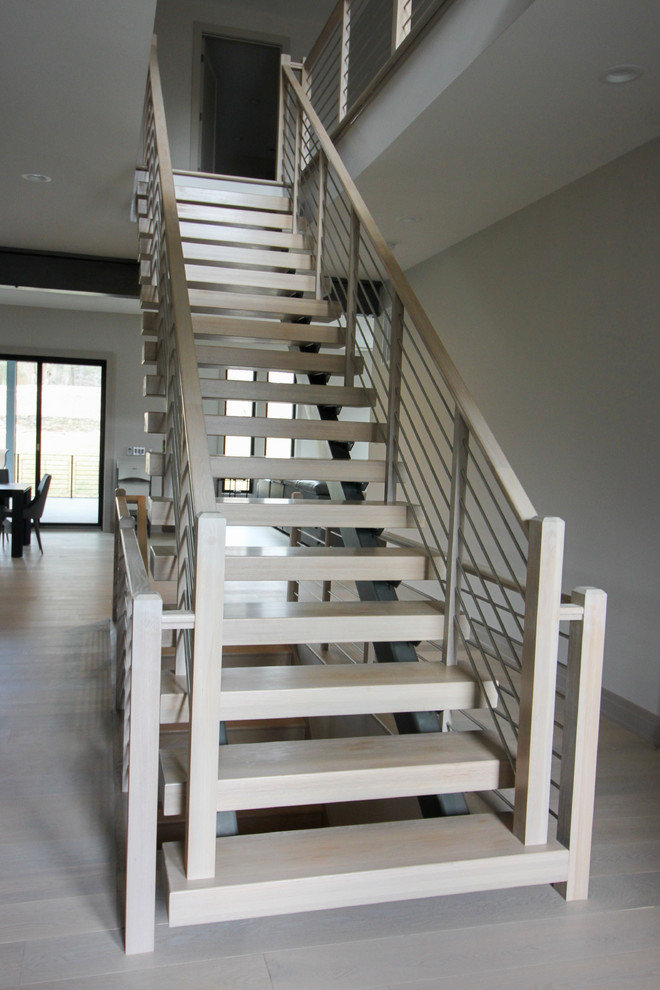 Idées déco pour un escalier flottant contemporain de taille moyenne avec des marches en bois et un garde-corps en métal.