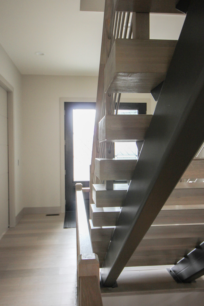 Imagen de escalera suspendida contemporánea de tamaño medio con escalones de madera y barandilla de metal