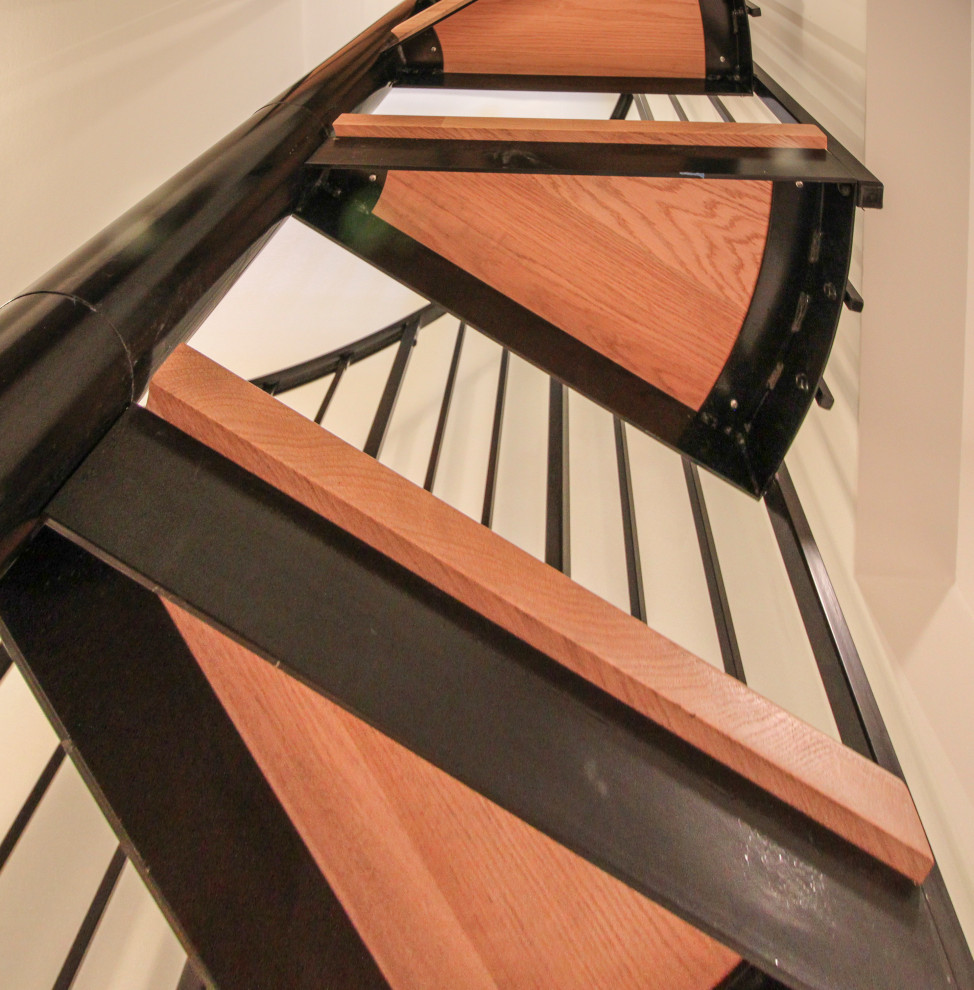 Imagen de escalera de caracol actual grande con escalones de madera, contrahuellas de madera y barandilla de varios materiales