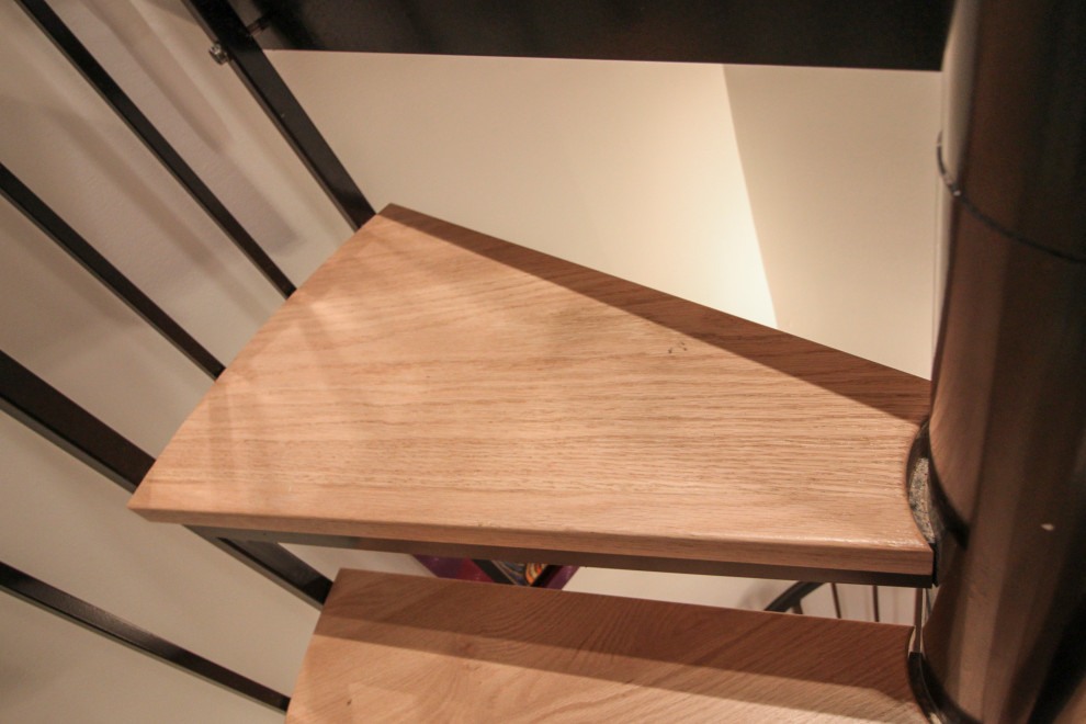 Modelo de escalera de caracol actual grande con escalones de madera, contrahuellas de madera y barandilla de varios materiales