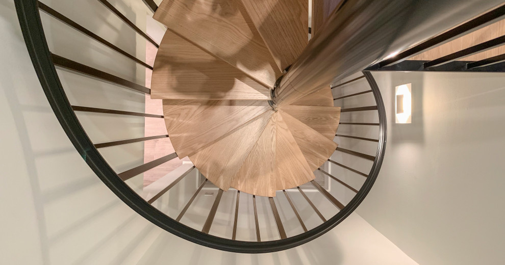 Immagine di una grande scala a chiocciola contemporanea con pedata in legno, alzata in legno e parapetto in materiali misti