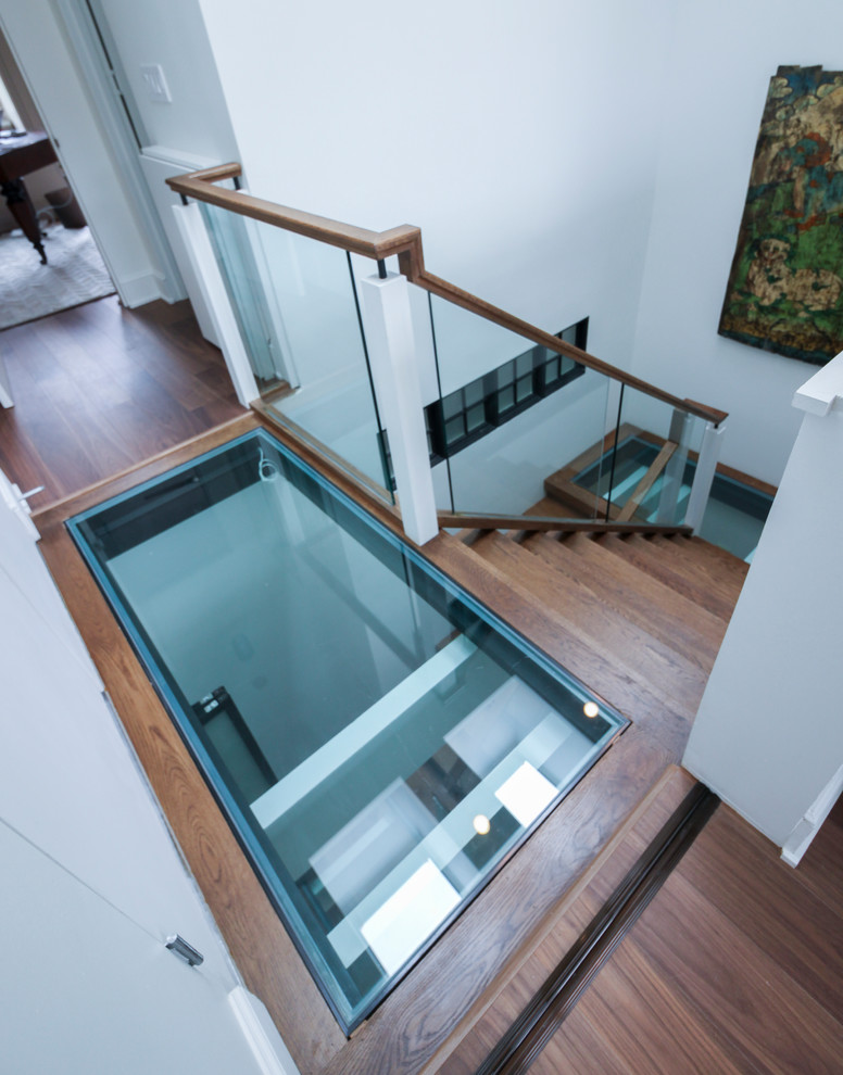 Cette image montre un très grand escalier sans contremarche flottant design avec des marches en verre et un garde-corps en verre.